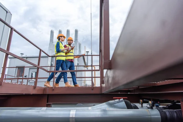 Ingenieros profesionales en chalecos de seguridad y cascos caminando sobre el techo - foto de stock