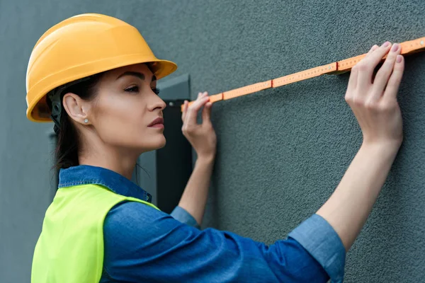 Architetto professionista femminile in hardhat parete di misura — Foto stock