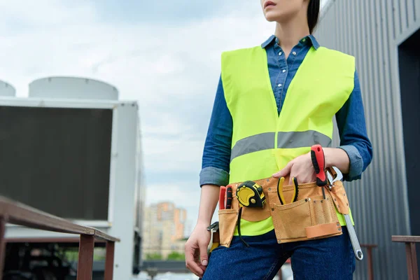 Ausgeschnittene Ansicht einer Ingenieurin mit Werkzeuggurt in Sicherheitsweste — Stockfoto