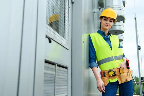 Arquitecta mujer con cinturón de herramientas en chaleco de seguridad y hardhat - foto de stock