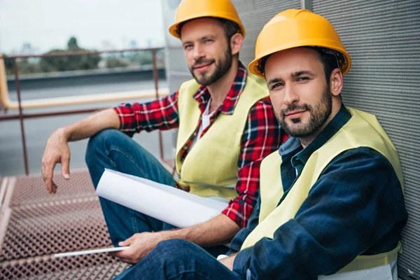 Architects working with blueprint sitting on construction on roof — Stock Photo