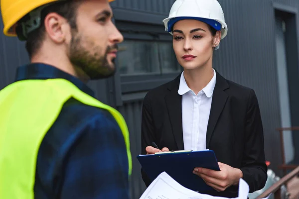 Selective focus of architect and builder in helmets working on construction — Stock Photo