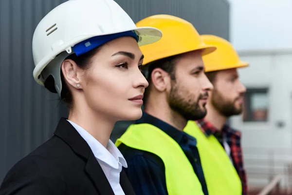 Female engineer and male workers in helmets on construction — Stock Photo