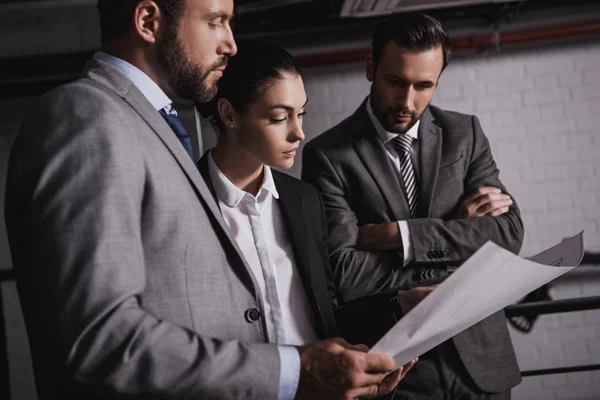 Arquitectos e ingenieros adultos en trajes que trabajan juntos con planos - foto de stock