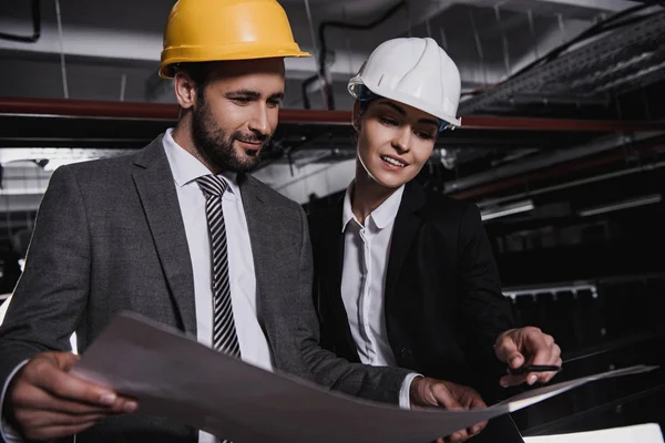 Ingénieurs en costumes et hardhats travaillant avec le plan directeur — Photo de stock