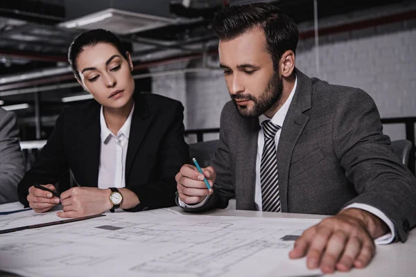 Architects in formal wear working with blueprints together — Stock Photo