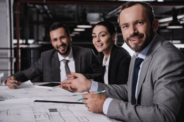 Male and female engineers in suits working with blueprints together — Stock Photo