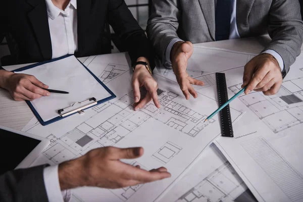 Cropped view of architects gesturing and working with blueprints — Stock Photo