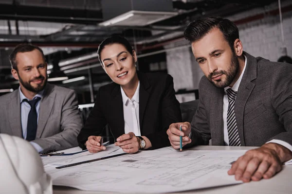 Ingenieure in Anzügen arbeiten gemeinsam mit Bauplänen — Stockfoto