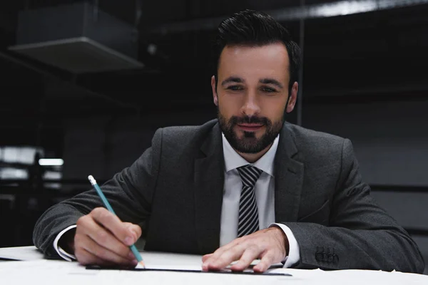 Усміхнений бізнесмен працює з кресленнями і олівцем — стокове фото