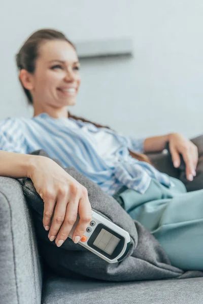 Вибірковий фокус жінки, що сидить на дивані з пультом дистанційного керування кондиціонером — стокове фото