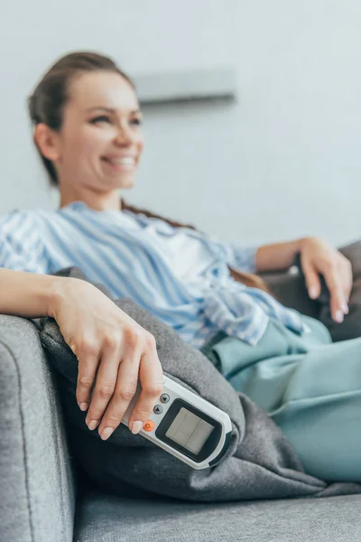 Foyer sélectif de la femme assise sur le canapé avec climatiseur télécommande — Photo de stock