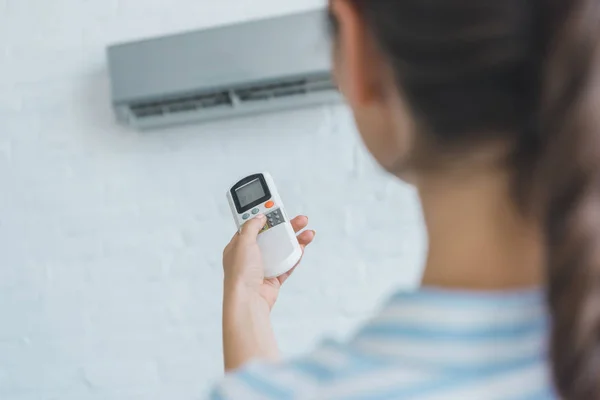 Selective focus of woman turning on air conditioner with remote control — Stock Photo