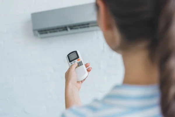 Messa a fuoco selettiva della donna accendere condizionatore d'aria con telecomando — Foto stock