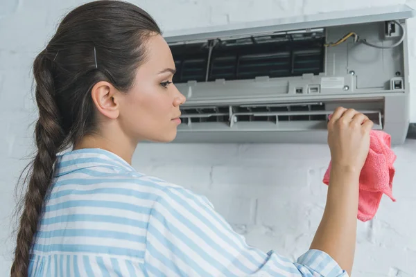 Rückansicht einer Frau, die Klimaanlage mit Lappen reinigt — Stockfoto