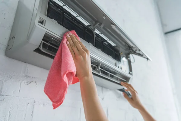 Vue recadrée de femme ouvrière nettoyage climatiseur avec chiffon — Photo de stock