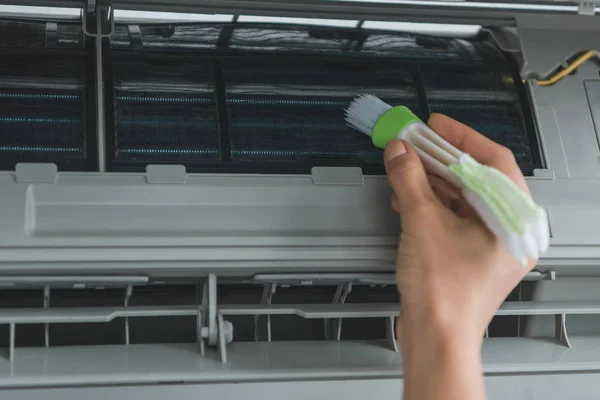 Partial view of female worker cleaning air conditioner with brush — Stock Photo