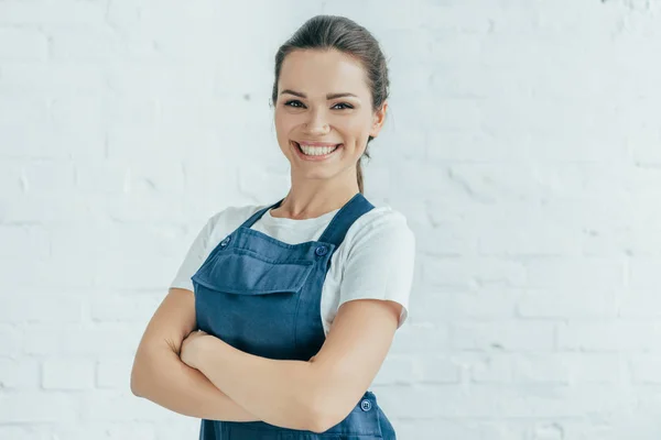 Sorridente operaia fiduciosa in uniforme posa con le braccia incrociate — Foto stock