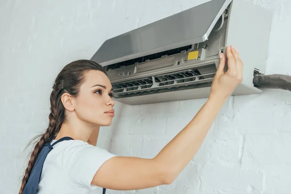 Beautiful female worker repairing air conditioner — Stock Photo