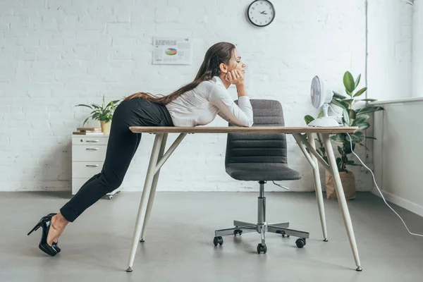 Mujer de negocios aire acondicionado con ventilador eléctrico en el lugar de trabajo en la oficina - foto de stock