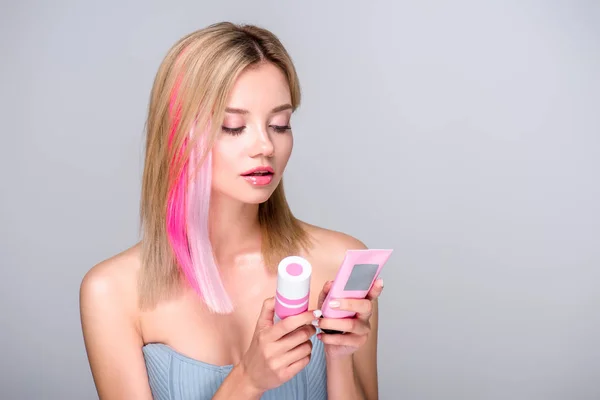 Schöne junge Frau mit farbigem Bob-Schnitt hält Haarpflegemittel isoliert auf grau — Stockfoto