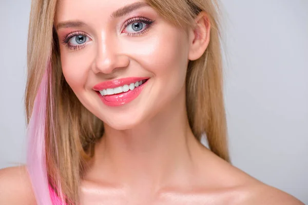 Close-up retrato de feliz jovem mulher com fio de cabelo rosa olhando para a câmera isolada no cinza — Fotografia de Stock