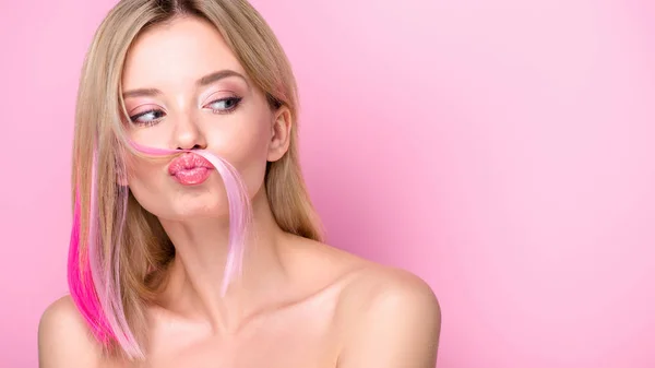 Funny young woman making mustache with pink hair strand isolated on pink — Stock Photo