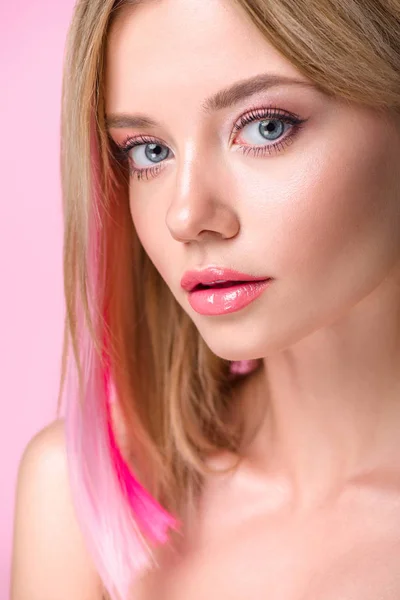 Close-up retrato de atraente jovem mulher com fios de cabelo coloridos olhando para a câmera isolada em rosa — Fotografia de Stock