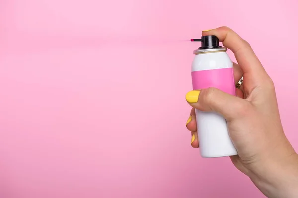 Colpo ritagliato di donna con unghie gialle che tengono vernice spray per capelli isolati su rosa — Foto stock