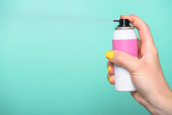 Tiro recortado de la mujer sosteniendo pintura en aerosol para el cabello aislado en turquesa — Stock Photo