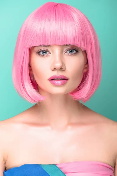 Retrato de cerca de la mujer joven con corte bob rosa y maquillaje elegante mirando a la cámara aislada en turquesa - foto de stock