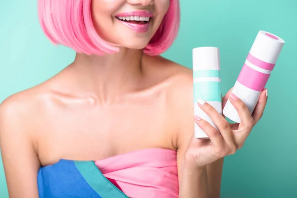 Tiro cortado de mulher jovem com bob rosa corte segurando latas de coloração sprays de cabelo isolado em turquesa — Fotografia de Stock