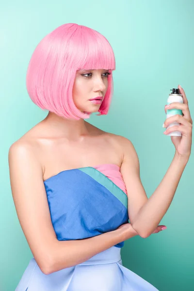 Stylish young woman with pink bob cut holding coloring hair spray isolated on turquoise — Stock Photo