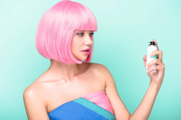 Beautiful young woman with pink bob cut holding coloring hair spray isolated on turquoise — Stock Photo