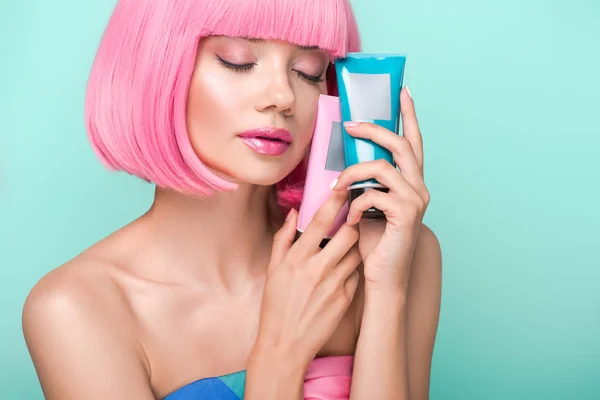 Sensual mujer joven con tubos de tónicos para colorear el cabello aislado en turquesa - foto de stock