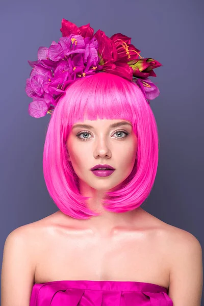 Close-up portrait of beautiful young woman with pink bob cut and flowers in hair looking at camera isolated on violet — Stock Photo