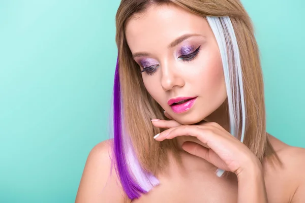 Close-up portrait of beautiful young woman with colorful strands in hair isolated on blue — Stock Photo