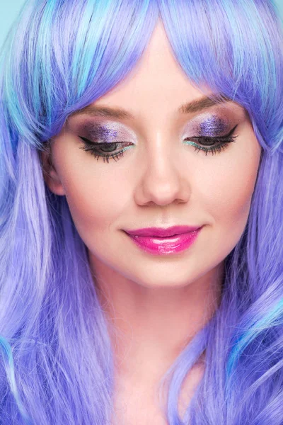 Retrato de cerca de la sensual joven con el pelo azul mirando hacia abajo aislado en azul - foto de stock