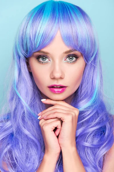 Красива молода жінка з блакитним волоссям дивиться на камеру ізольовано на синьому — стокове фото
