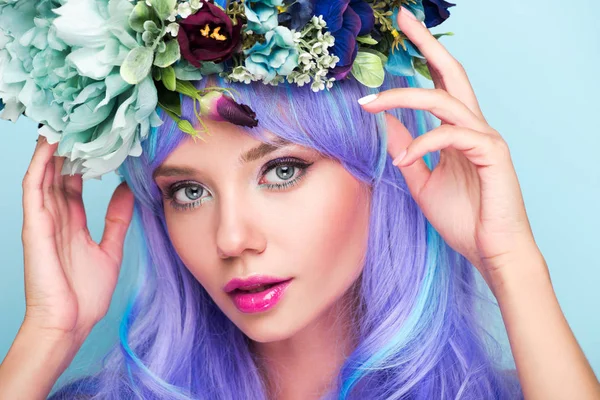 Close-up retrato de jovem mulher com cabelo azul encaracolado e coroa floral isolado em azul — Fotografia de Stock