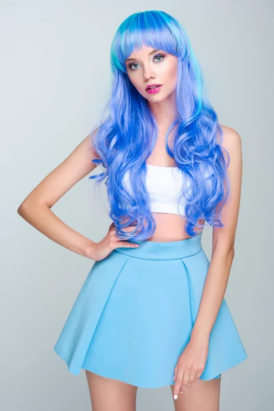Обрезанный снимок молодой женщины с кудрявыми ярко-голубыми волосами, изолированными на сером — стоковое фото