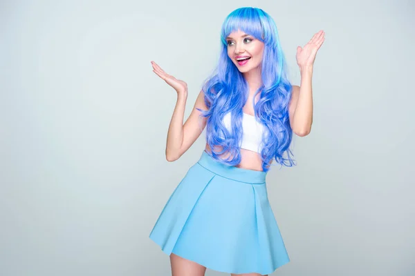 Excité jeune femme avec des cheveux bleu vif et les mains levées isolé sur gris — Photo de stock