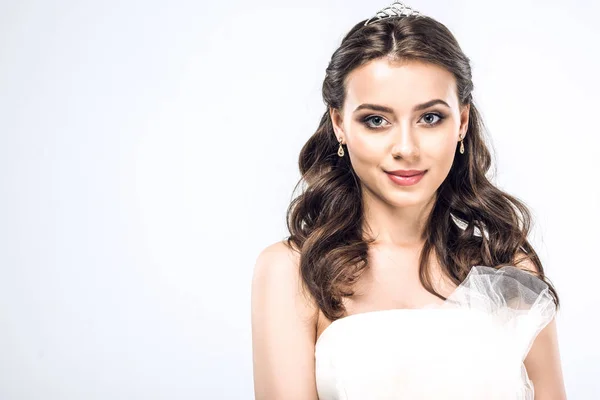 Close-up portrait of young bride in wedding dress with earrings and tiara isolated on white — Stock Photo