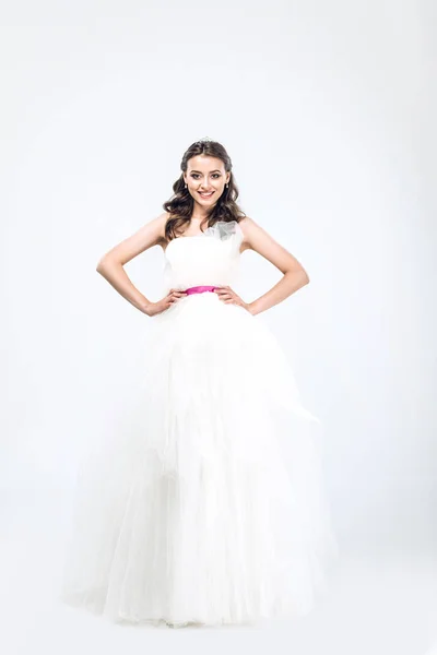 Young bride in wedding dress with arms akimbo looking at camera on white — Stock Photo