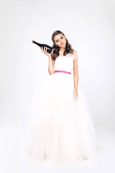 Attraktive junge Braut im Brautkleid mit einer Flasche Champagner auf weißem Grund — Stockfoto