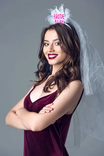 Sorrir futura noiva em véu para a despedida de solteira com braços cruzados olhando para a câmera isolada no cinza — Fotografia de Stock
