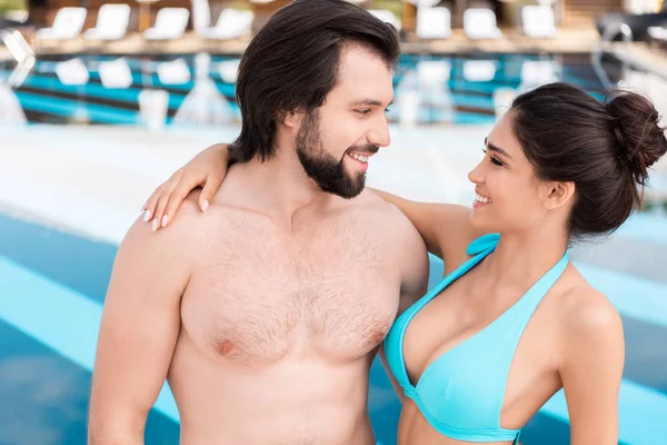 Schönes lächelndes Paar, das sich in der Nähe des Schwimmbades umarmt und ansieht — Stockfoto