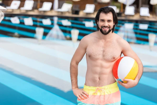 Bearded man with inflatable ball standing at swimming pool — Stock Photo