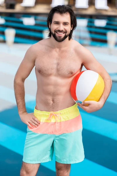Schöner Mann mit aufblasbarem Ball, der in der Nähe von Schwimmbad steht — Stockfoto