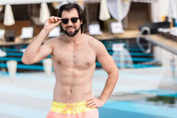 Schöner bärtiger Mann mit Sonnenbrille posiert am Schwimmbad — Stockfoto